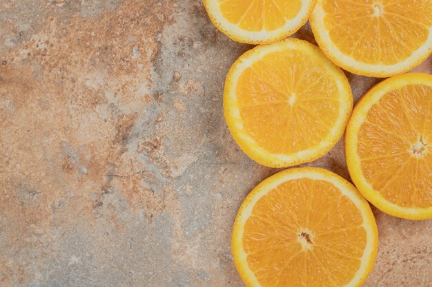 Jugosas rodajas de naranja sobre fondo de mármol.