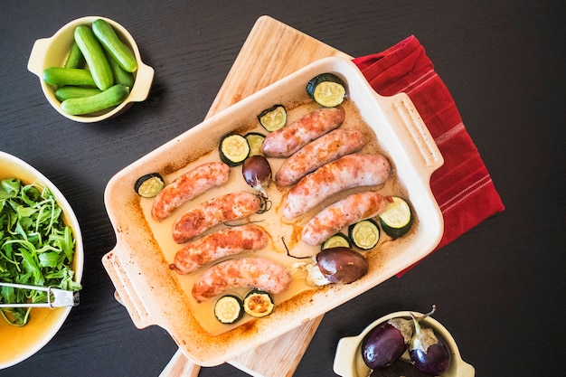 Jugosas salchichas con verduras en una bandeja para hornear