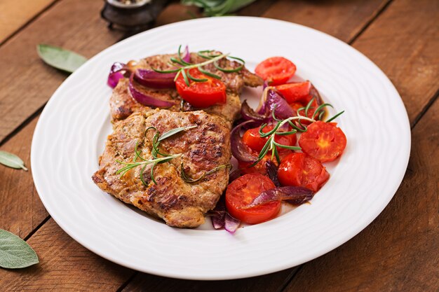 Jugoso filete de cerdo con romero y tomates en un plato blanco