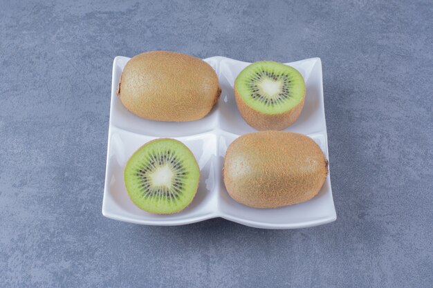 Jugosos kiwis en una mesa de mármol plateon.