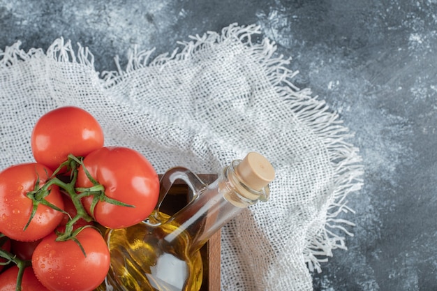 Unos jugosos tomates con una botella de vidrio de aceite.