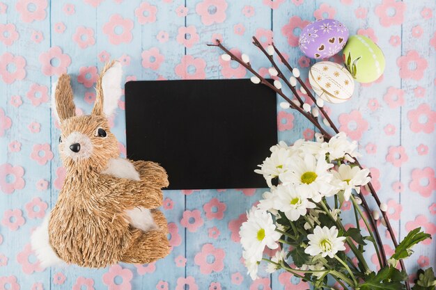 Juguete de conejo cerca de papel y símbolos de Pascua