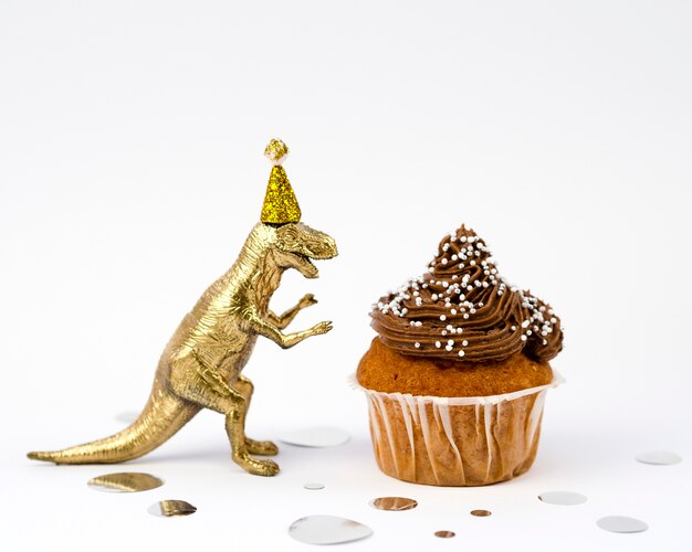 Juguete dorado dinosaurio y sabroso muffin