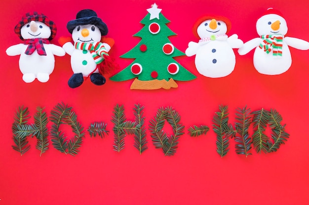 Juguete muñecos de nieve y árbol de navidad cerca de inscripción.