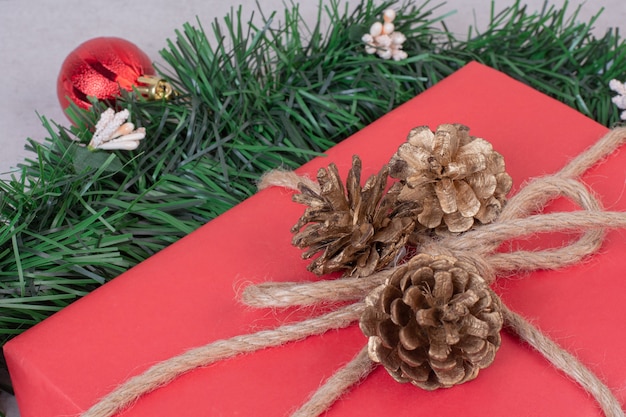 Juguete de piña de Navidad con caja roja sobre superficie gris