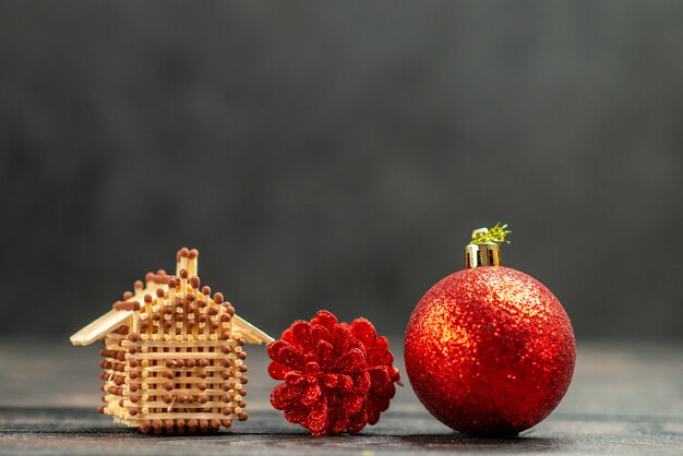 Los juguetes del árbol de navidad de la vista frontal coinciden con la casa en el espacio libre oscuro del fondo aislado