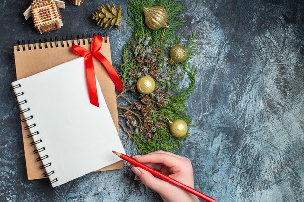 Juguetes de árbol de Navidad de vista superior con bloc de notas sobre fondo claro-oscuro