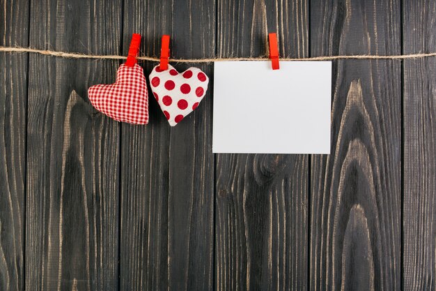 Juguetes de corazon colgando de una cuerda con tarjeta en blanco