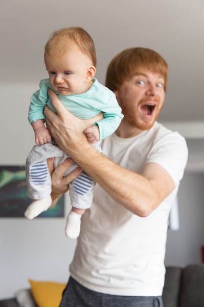 Juguetón emocionado nuevo padre con dulce bebé