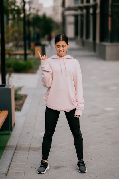 Juguetón retrato de mujer joven y bonita divirtiéndose en la calle