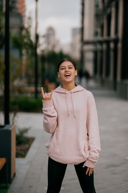 Juguetón retrato de mujer joven y bonita divirtiéndose en la calle