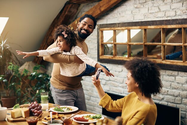 Juguetona familia afroamericana divirtiéndose en el comedor