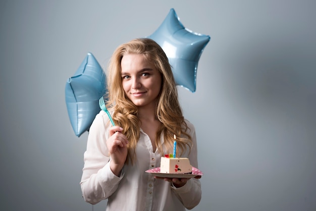 Juguetona joven comiendo pastel de cumpleaños