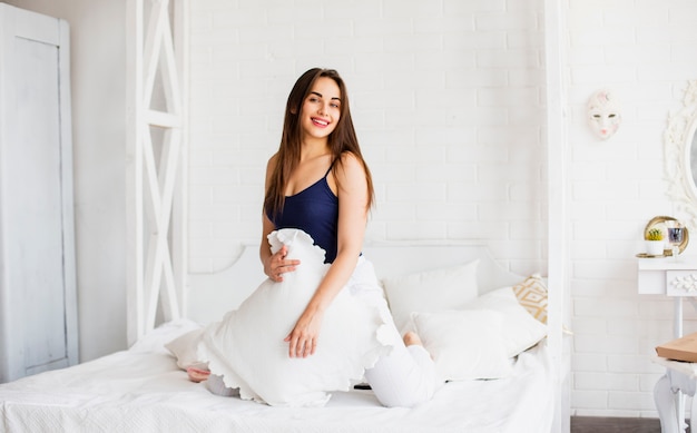 Juguetona mujer en la cama con almohada