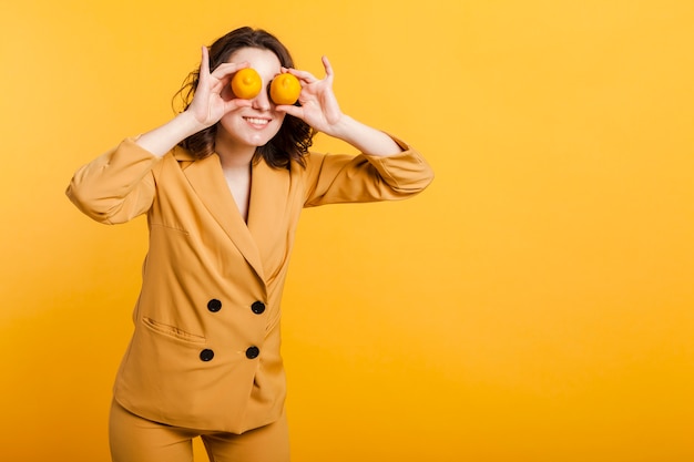 Juguetona mujer cubriendo los ojos con limones