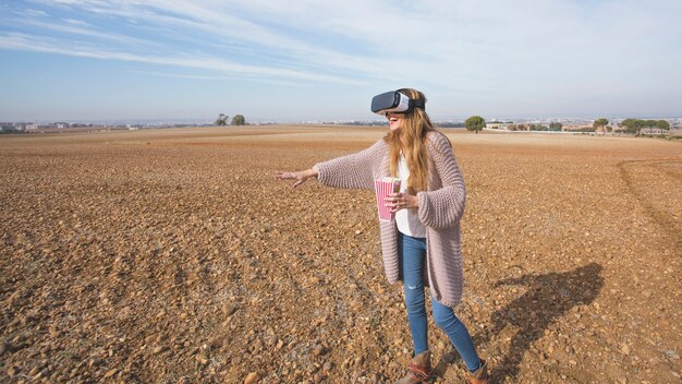 Juguetona mujer disfrutando de VR en el campo