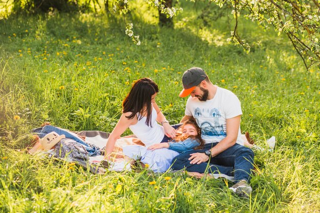 Junte la mirada de la hija que se sienta en hierba verde en el parque