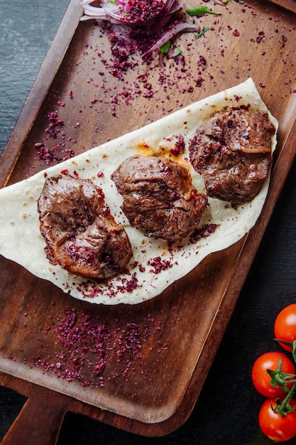 Kabab de carne servido con cebolla agracejo y tomates