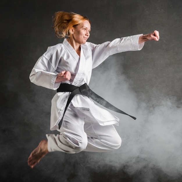 Foto gratuita karate mujer saltando tiro completo