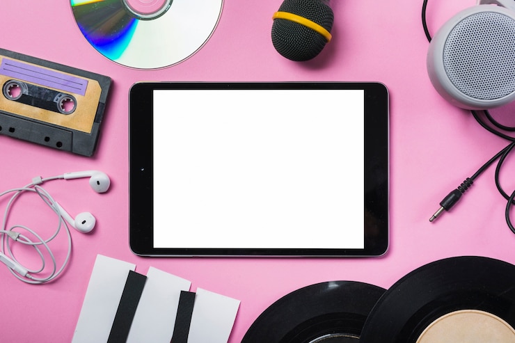 Photo Gratis kaset; cd; earphone; piringan hitam (vinyl); mikrofon; speaker; tuts piano kertas di sekitar tablet digital dengan latar belakang merah muda