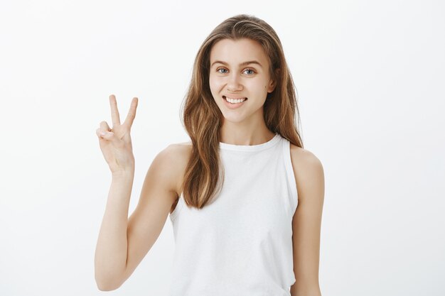 Kawaii joven mujer caucásica mostrando gesto de paz y sonriendo con dientes blancos