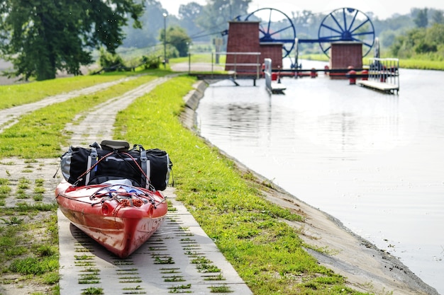 Un kayak con una bolsa de viaje junto al canal de Elblag en el escenario de un monumento histórico en Polonia