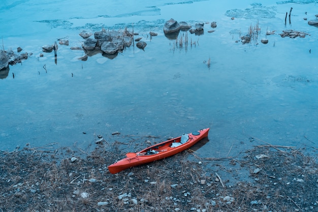 Foto gratuita kayak se encuentra en una playa salvaje de un lago salvaje