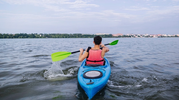 Kayaker salpicaduras de agua con remo mientras kayak