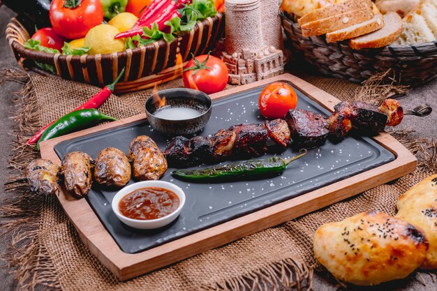Kebab de carne sobre tabla de madera patata pimiento tomate adjika