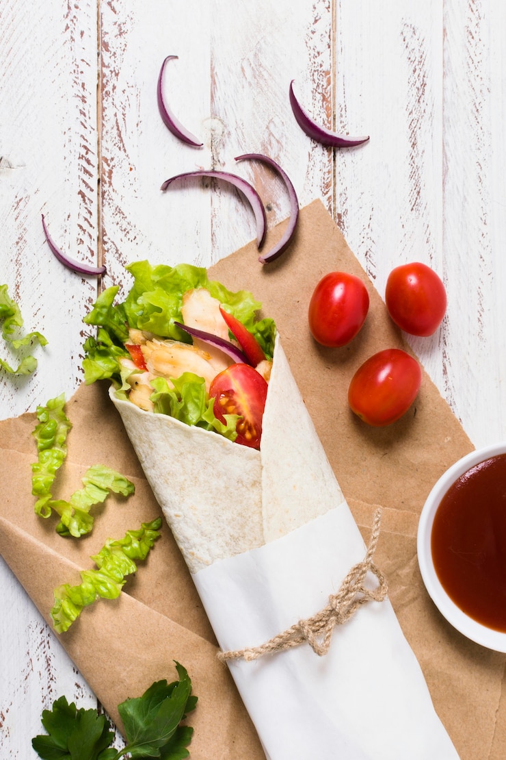 Foto gratuito kebab de carne y verduras cocidas envuelto en papel