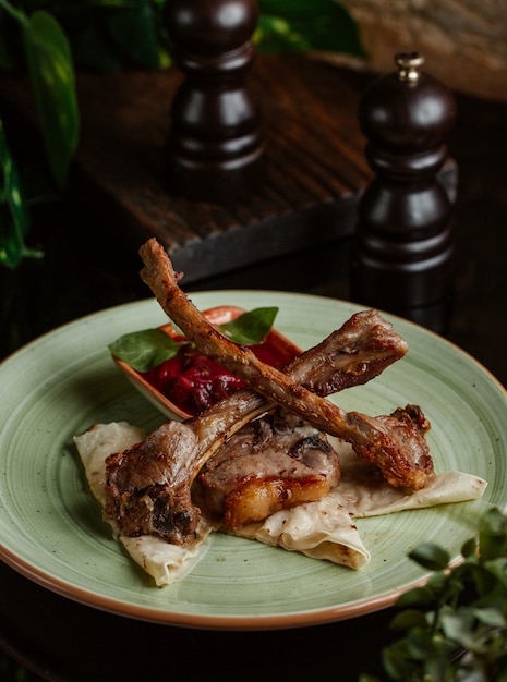 Foto gratuita kebab de cordero con salsa de tomate dentro de un plato de cerámica verde