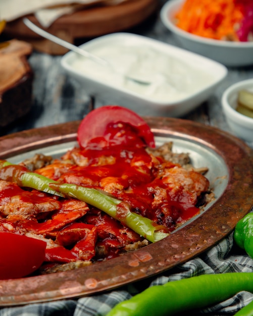 Kebab de iskender turco con salsa de tomate y chile verde.