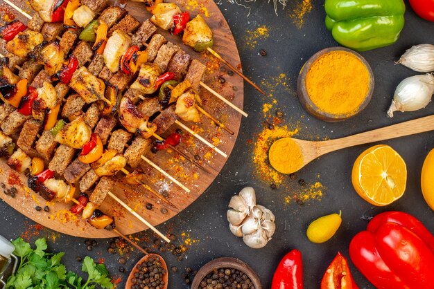 Kebab de pollo fácil de vista superior en tablero de madera y otras cosas en la mesa oscura