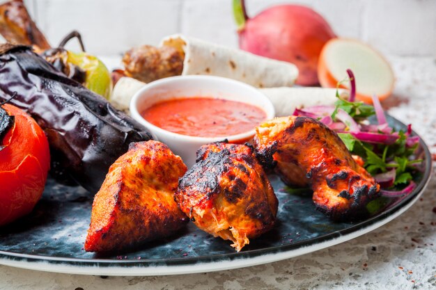 kebab de pollo con salsa y berenjenas fritas y cebolla en plato redondo