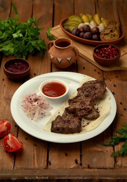 Kebab de ternera marinado servido con mezcla de cebolla y zumaque, salsa de tomate y hierbas