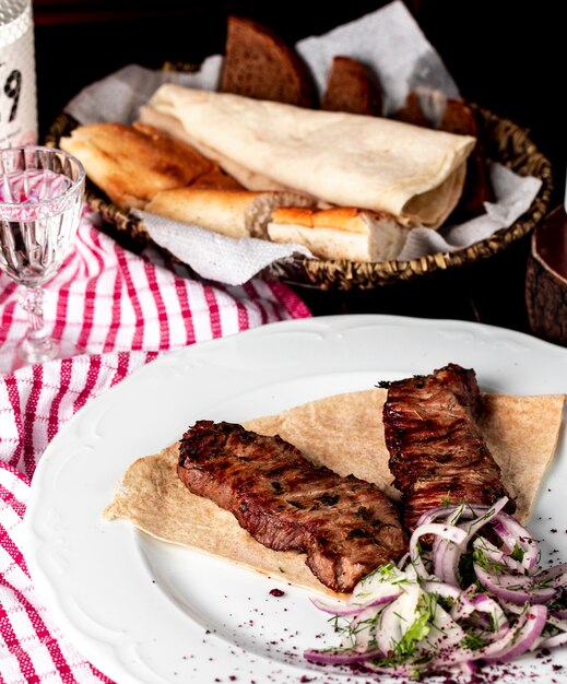 Kebab tradicional azerbaiyano, barbacoa en lavash con sumakh, cebolla y ensalada verde.