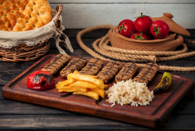 Kebabs de lula de res servidos con arroz, papas fritas, tomate a la parrilla y pimientos