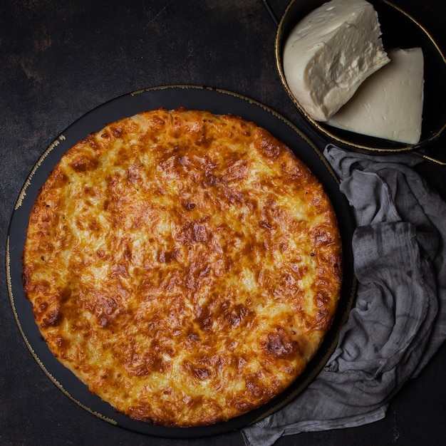 Khachapuri de vista superior con queso sulguni en plato oscuro