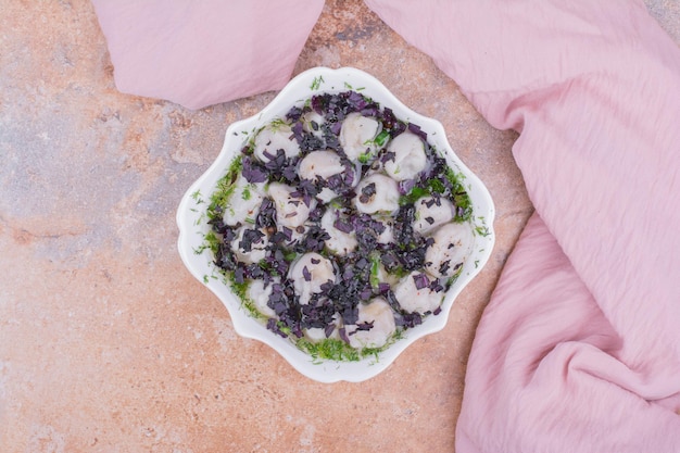 Khinkali caucásico crudo con hierbas picadas en un bol.