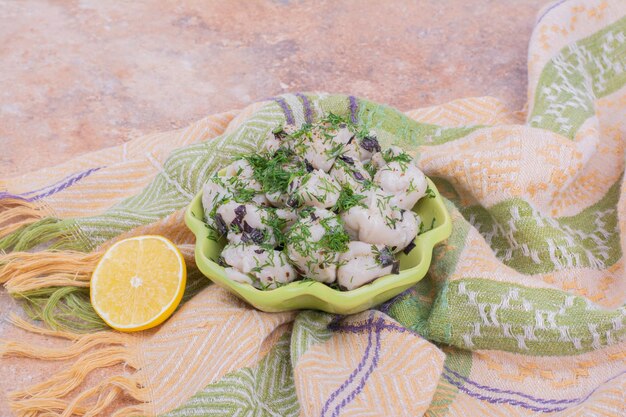 Khinkali caucásico crudo con hierbas picadas en un bol.