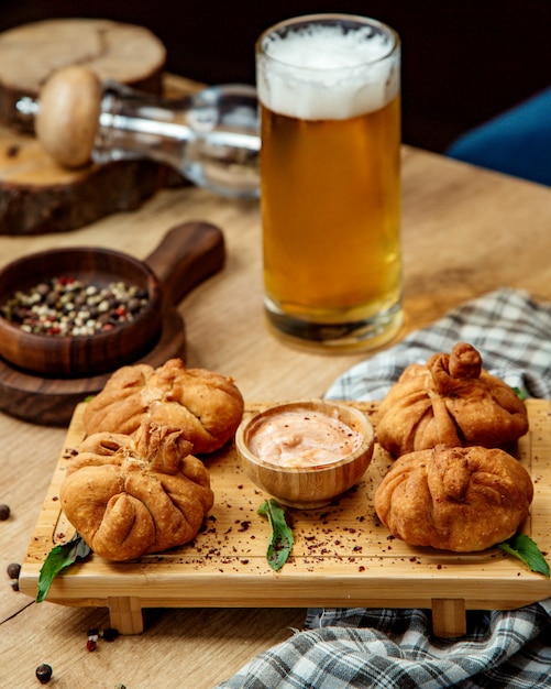 Foto gratuita khinkali georgiano frito con salsa en una bandeja de madera