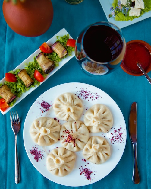 Khinkali servido con rollos de berenjena y copa de vino