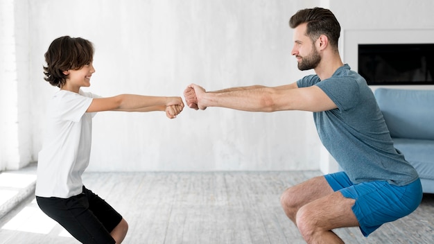 Foto gratuita kid y su padre haciendo deporte en casa