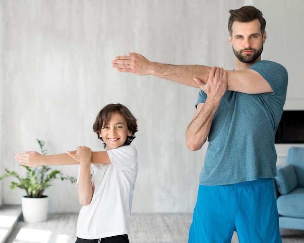 Foto gratuita kid y su padre haciendo deporte en casa