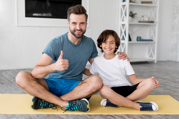 Foto gratuita kid y su padre haciendo deporte en casa