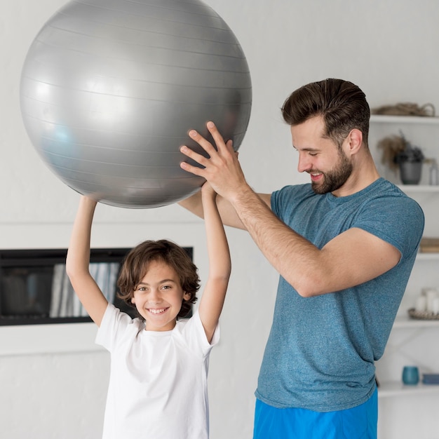 Foto gratuita kid y su padre haciendo deporte en casa