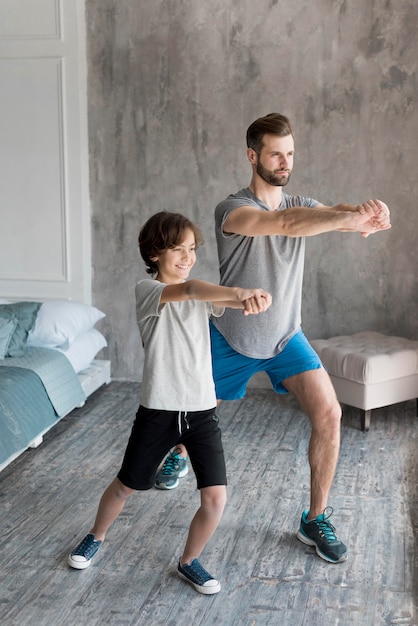 Foto gratuita kid y su padre haciendo deporte en casa