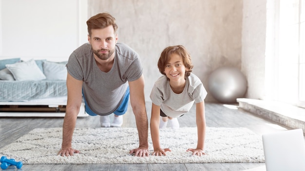 Kid y su padre haciendo deporte en casa