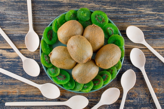 Foto gratuita kiwi en una bandeja con rodajas secas, cucharas planas yacen sobre un fondo de madera