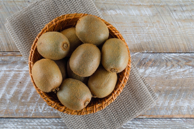 Kiwi en una canasta de mimbre en la mesa de madera, plano.